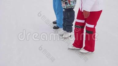 幼儿在溜冰鞋上的第一步.. <strong>爸爸妈妈</strong>教一个孩子滑冰，双手握在冰上.. 家庭