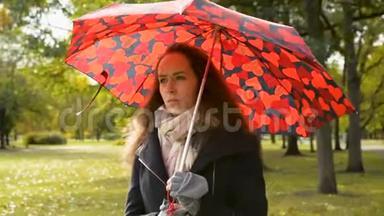 金秋时节，一位戴着红色大伞的漂亮女士在公园散步