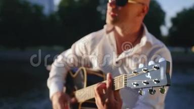 人在公园里弹吉他，对着湖边唱歌.. 吉他手触摸吉他弦。 中弹。