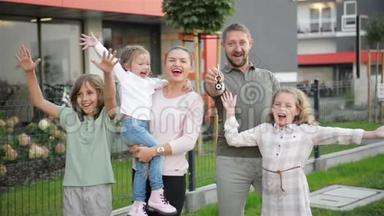 有孩子的家庭看着摄像机站在街道的户外。 夫妻和孩子买新家。 房地<strong>产业</strong>主