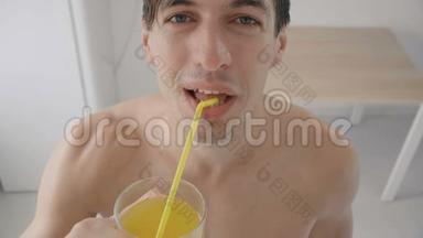 在炎热的夏天，年轻人在厨房里用管子喝着清爽的橘子汽水