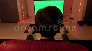 一个少年<strong>坐在</strong>一张红色的椅子<strong>前</strong>的绿色<strong>电脑</strong>屏幕。