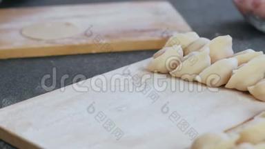 女人用肉馅包饺子，特写的手。 把饺子放在木板上。