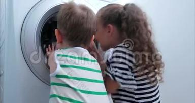 可爱的孩子们看着洗衣机里面。 气缸旋压机.. 工业概念洗衣机