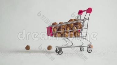 超市里的购物车里装满了榛子坚果。 榛子掉进超市手推车里。