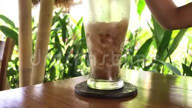 在热带背景下，在巴厘岛，<strong>倒</strong>入带有冰的软饮料<strong>可乐</strong>。