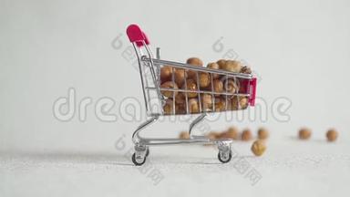 超市里的购物车里装满了榛子坚果。 榛子掉进超市手推车里。