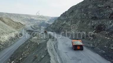 采石场自卸卡车俯视图.. 自卸卡车行驶在布满灰尘的露天采矿道路上。 重型运输