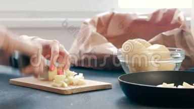 特写女人`她的手在木板上切一个土豆，然后把它放在一个<strong>油炸锅</strong>上。