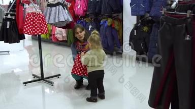 一个可爱的小女孩和她的母亲在一家精品店里家精品店。 妈妈和孩子在商店里挑选衣服
