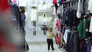 一个可爱的小女孩和她的母亲在一家<strong>精品</strong>店里家<strong>精品</strong>店。 妈妈和孩子在商店里选择衣服。