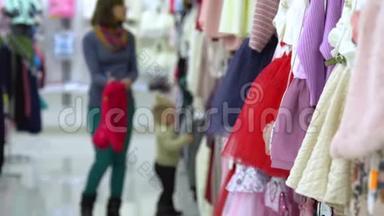 一个可爱的小女孩和她的母亲在一家精品店里家精品店。 妈妈和孩子在商店里选择衣服。