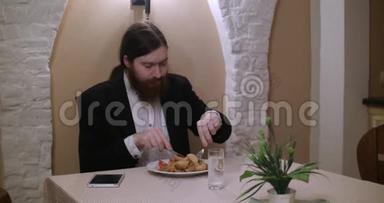 一个留胡子的年轻人在餐馆吃饭，用平板电脑