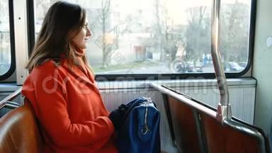 穿着橙色外套，背着蓝色袋子的可爱女孩乘坐<strong>公共交通工具</strong>。 布鲁内特透过电车窗和