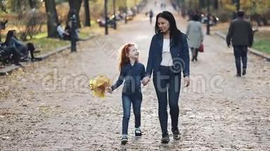 一位美丽的母亲和她可爱的小女儿在<strong>秋</strong>天的公园里散步。 他们在人群中间走<strong>来</strong>走<strong>去</strong>