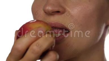健康的女人吃白色背景的红苹果。特写嘴唇。健康食品和节食理念。慢动作