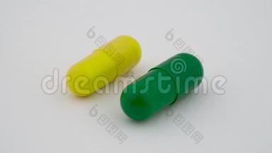两个硬淀粉胶囊旋转在<strong>转盘</strong>上。 <strong>黄色</strong>和绿色。 孤立在白色背景上。 关门