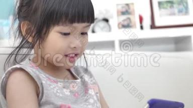 小亚洲女孩在家里微笑<strong>着看着手机</strong>。