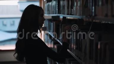 图书馆书架前一个女孩看书的剪影