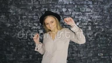 一个戴着黑帽子<strong>的</strong>女孩正在一面<strong>有质感的</strong>墙上跳舞