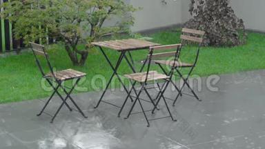 大雨在后院和潮湿的家具上倾盆大雨。 一张桌子和一张桌子。