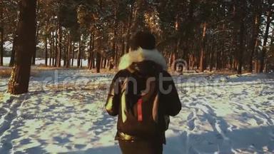一个年轻的白种人女孩背着背包在冬天的森林<strong>道路</strong>上，在日落时<strong>覆盖</strong>着冬天的松林。 步行