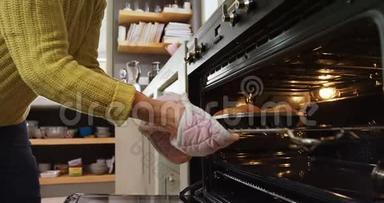 老太太戴着烤箱手套，从4K4k烤箱里取出刚出炉的松饼
