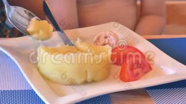 一个女人的勺子收集土豆泥和西红柿，并喂养<strong>婴儿</strong>。