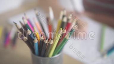 桌上一堆彩色铅笔。 相机幻灯片。 一个女人的手拿着一支铅笔在一个