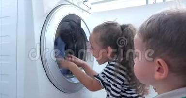 可爱的孩子们在洗衣机里看。 气缸旋转机。 概念洗衣机，工业