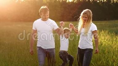 幸福的家庭，<strong>爸爸妈妈</strong>和儿子在情感上散步。 在新鲜空气中的绿色田野里奔跑和享受生活，蓝色