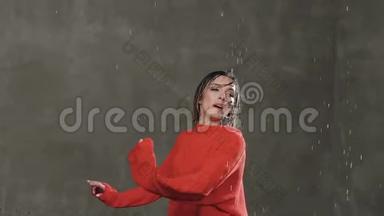 现代舞。 湿漉漉的女孩舞蹈演员在雨水下的工作室里，在工作室的女孩面前，绕着自己旋转