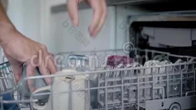 男人正在厨房里从洗碗机里拿出一个餐具，清洗干净后，用手特写，放在桌子上