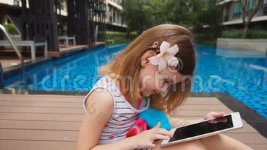 漂亮的<strong>女孩子</strong>在游泳池附近触摸平板电脑