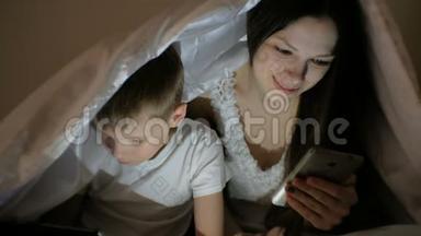 年轻漂亮的妈妈在手机上浏览互联网，而她的儿子在<strong>平板</strong>电脑上看<strong>卡通</strong>。