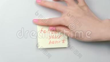 特写女人`她的手贴着黄色的贴纸纸，文字跟随你的心。