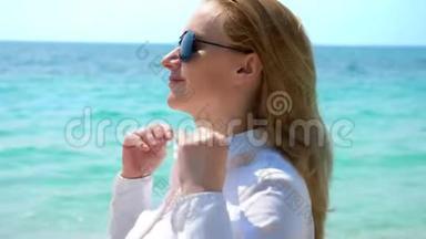 在海滩上戴太阳镜的女商人。 她在大海和太阳中快乐。 她解开衬衫<strong>扣子</strong>，呼吸着