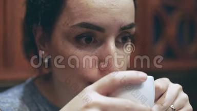年轻女子坐在咖啡馆里，喜欢闻咖啡，喝咖啡