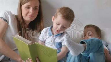 家庭妈妈和两个<strong>双胞胎兄弟</strong>蹒跚学步的孩子在床上看书。 家庭阅读时间。