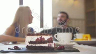 在一对夫妇面前吃着甜蛋糕，坐在咖啡馆里享受着交谈