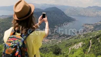 年轻的女游客带着帽子和黄色衬衫在手机上拍照。 旅行者在科托湾拍照