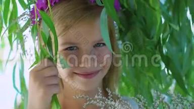 一个戴着花冠的金发小女孩在4K的树枝上对着镜头摆姿势