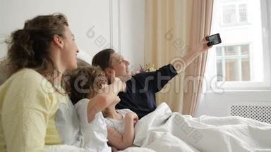 帅哥正在用他的智能手机拍照。 积极的家庭自<strong>我与</strong>母亲，父亲和两个孩子躺在一起