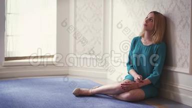坐在地板上，靠着墙，靠近窗户的灯光房里，沉思的女人