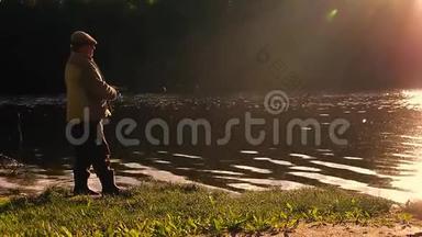 钓竿湖钓鱼男子夏季钓鱼，吸引日落水户外日出鱼群镜头.
