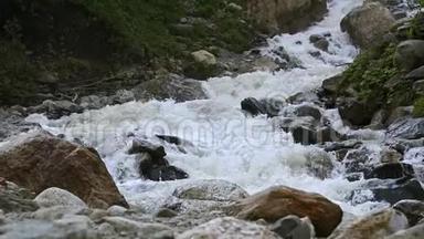 慢动作的水从一块巨大的岩石上掉下来。 阴天有小雨的自然环境中的瀑布