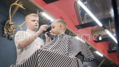理发师在理发店和理发店里用梳子和吹风机为一个小男孩做发型
