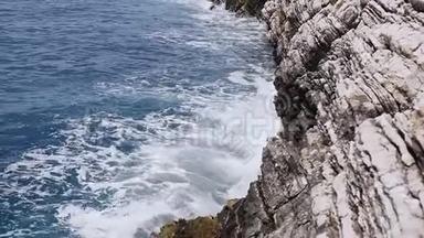 美丽的波浪飞溅在Petrovac的层状岩石悬崖上。 黑山，亚得里亚海。 海浪拍打着岩石