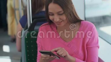 年轻快乐的女人在旅行中坐在靠近窗户的<strong>公共交通</strong>工具上使用智能手机。
