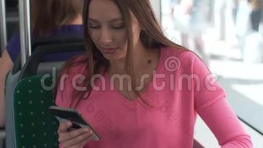 年轻快乐的女人在旅行中坐在靠近窗户的公共<strong>交通工具</strong>上使用智能手机。